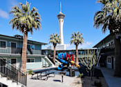 Thumbnail 20 of 20 - A playground with a slide and a tower in the background.