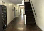 Thumbnail 15 of 15 - A long hallway with a staircase on the right and a door at the end.