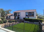 Thumbnail 12 of 20 - A house with a black fence and green lawn in front.