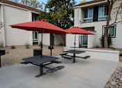 Thumbnail 8 of 20 - A red umbrella is on a table outside a house.