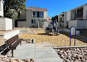 Thumbnail 10 of 20 - A park area with a bench and a playground.