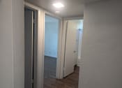 Thumbnail 17 of 20 - A hallway with a door on the left and another door on the right.