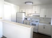 Thumbnail 16 of 20 - A kitchen with white appliances and cabinets.