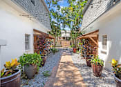 Thumbnail 22 of 30 - a courtyard with potted plants and a white building with a gray roof
