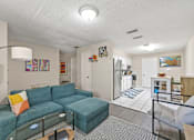 Thumbnail 5 of 19 - A living room with a blue couch and a glass table.