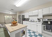 Thumbnail 2 of 19 - A kitchen with white cabinets and a wooden island.