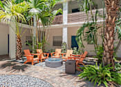 Thumbnail 23 of 30 - a patio with a fire pit and chairs in front of a building