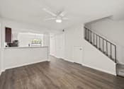 Thumbnail 7 of 16 - A spacious room with a staircase and a ceiling fan.