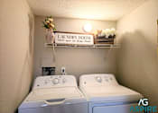 Thumbnail 34 of 56 - A small laundry room with two washing machines and a shelf above them.