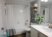Thumbnail 24 of 56 - A bathroom with a white shower curtain, a toilet, a sink, and a mirror.