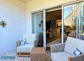 Thumbnail 42 of 56 - A patio with a white couch, a wooden chair, and a table with a brown and white checkered tablecloth.
