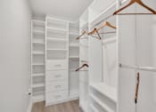 Thumbnail 19 of 22 - a walk in closet with white walls and wooden shelves and hangers