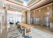 Thumbnail 2 of 36 - A large wooden table is surrounded by chairs in a spacious room with a patterned carpet.