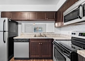 Thumbnail 7 of 32 - a kitchen with dark wood cabinets and white countertops