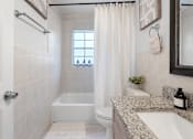 Thumbnail 16 of 30 - a bathroom with a white toilet next to a bathtub with a shower curtain