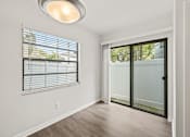 Thumbnail 10 of 16 - A room with a sliding glass door and a window with blinds.