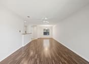 Thumbnail 4 of 16 - A long empty room with wooden floors and white walls.