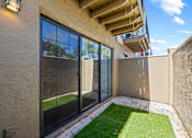 Thumbnail 12 of 16 - A patio with a glass door and a small lawn.