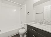 Thumbnail 14 of 16 - A white bathroom with a toilet, sink, and tub.