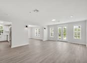 Thumbnail 9 of 22 - an empty living room with a kitchen in the background