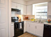 Thumbnail 8 of 28 - A kitchen with black appliances and white cabinets.