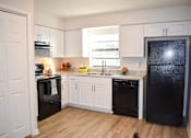 Thumbnail 9 of 28 - A kitchen with black appliances and white cabinets.