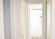 Thumbnail 24 of 28 - A long hallway with white walls and wood flooring.
