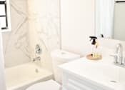 Thumbnail 21 of 28 - A white bathroom with a toilet, sink, and bathtub.