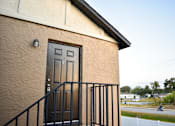 Thumbnail 7 of 28 - A brown house with a black door and a black railing.