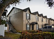 Thumbnail 6 of 28 - A beige house with black roof and a tree in front.