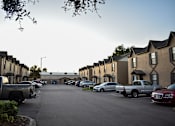 Thumbnail 4 of 28 - A parking lot with cars and trucks in front of apartment buildings.