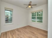 Thumbnail 27 of 40 - an empty living room with a ceiling fan and two windows