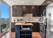 Thumbnail 5 of 114 - A fully equipped kitchen with high-end stainless steel appliances & modern cabinetry in Houston.