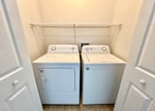 Thumbnail 16 of 16 - Two white front loading washing machines in a laundry room.