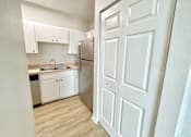 Thumbnail 11 of 16 - A white kitchen with a refrigerator and sink.