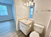 Thumbnail 7 of 16 - A white toilet sits next to a sink in a bathroom.