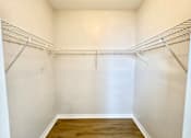 Thumbnail 12 of 16 - A white closet with a wooden floor and metal shelves.