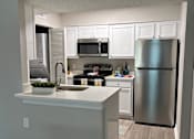 Thumbnail 66 of 75 - A kitchen with a refrigerator, microwave, and oven.