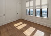 Thumbnail 38 of 40 - A room with wooden floors and a window overlooking a cityscape.