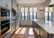 Thumbnail 36 of 40 - The Penthouse  A modern kitchen with stainless steel appliances and a view of the city.