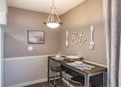 Thumbnail 11 of 20 - A dining area with a table set for two and a framed picture on the wall.