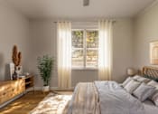 Thumbnail 10 of 13 - A bedroom with a large bed and a potted plant.