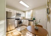 Thumbnail 9 of 13 - A kitchen with a table and chairs in the middle of it.