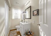 Thumbnail 13 of 13 - A white bathroom with a toilet, sink, and mirror.