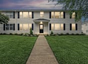 Thumbnail 1 of 13 - A building with a black door and windows with shutters.