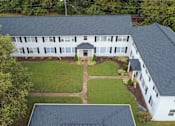 Thumbnail 4 of 13 - A white building with a black roof and a green lawn in front.