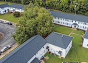 Thumbnail 5 of 13 - A white building with a black roof is surrounded by a green lawn.