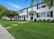 Thumbnail 6 of 13 - A white two-story apartment building with a black front door and windows.