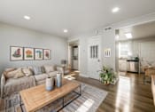 Thumbnail 8 of 13 - A living room with a couch, a coffee table, and a painting on the wall.