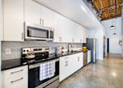 Thumbnail 2 of 8 - A modern kitchen with white cabinets and black countertops at Judson Mill Lofts, Greenville, 29611